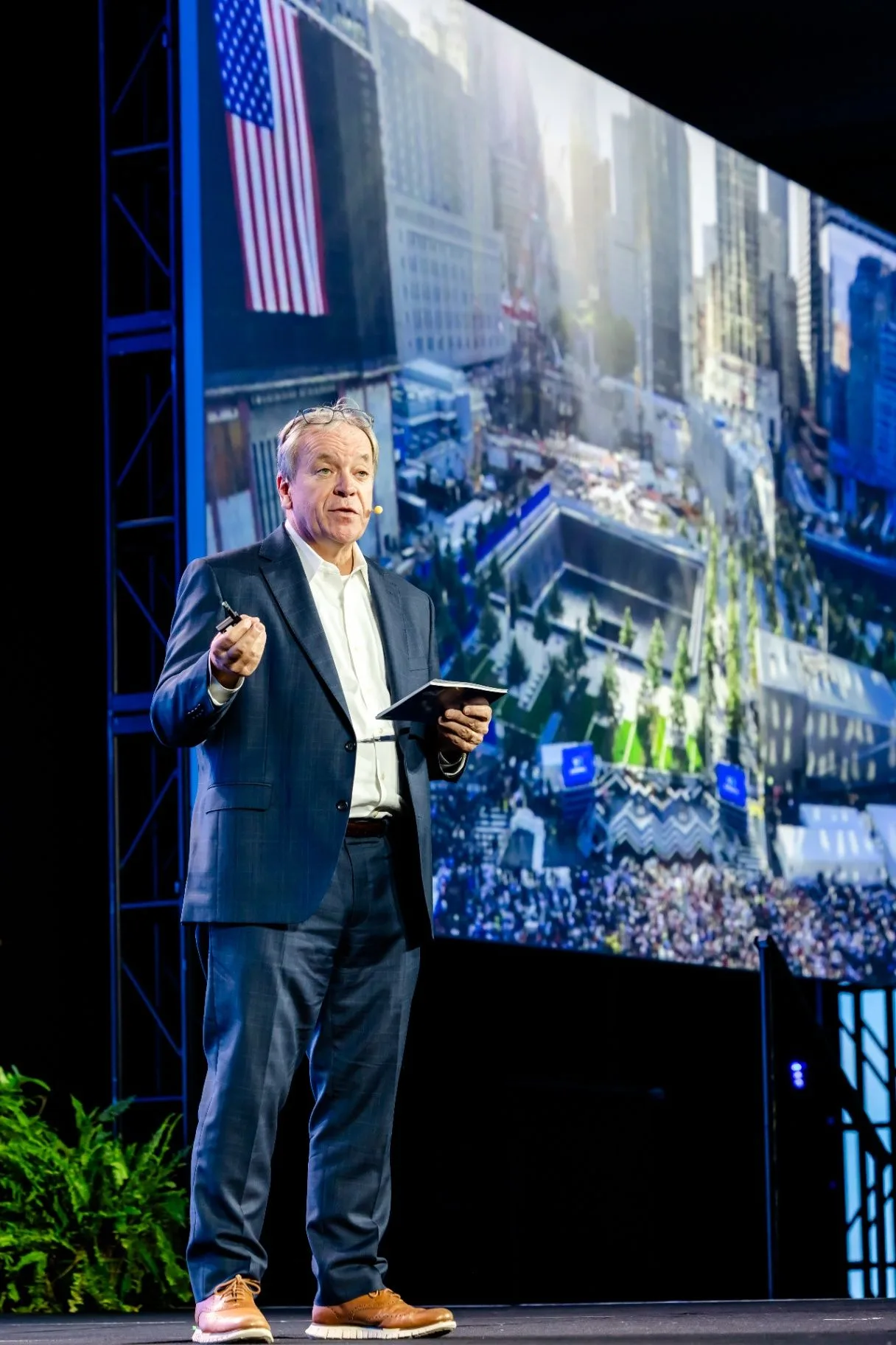 Corporate speaker presenting beside a large event screen